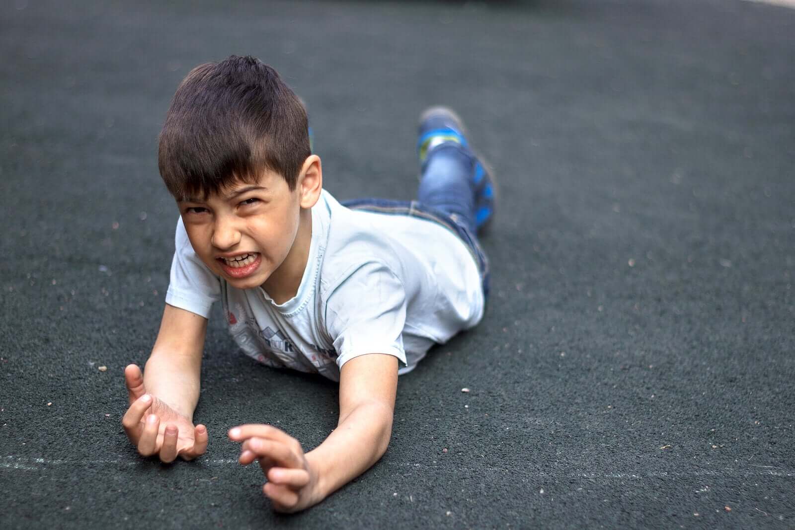 Et barn som har snublet og falt forover på sementen.