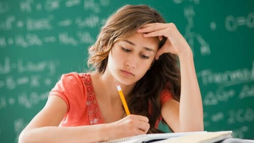A teenage girl doing homework, looking bored.