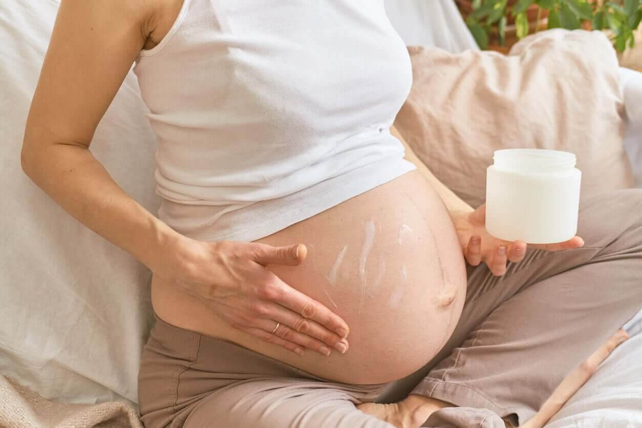 A pregnant woman applying moisturizer to her belly.