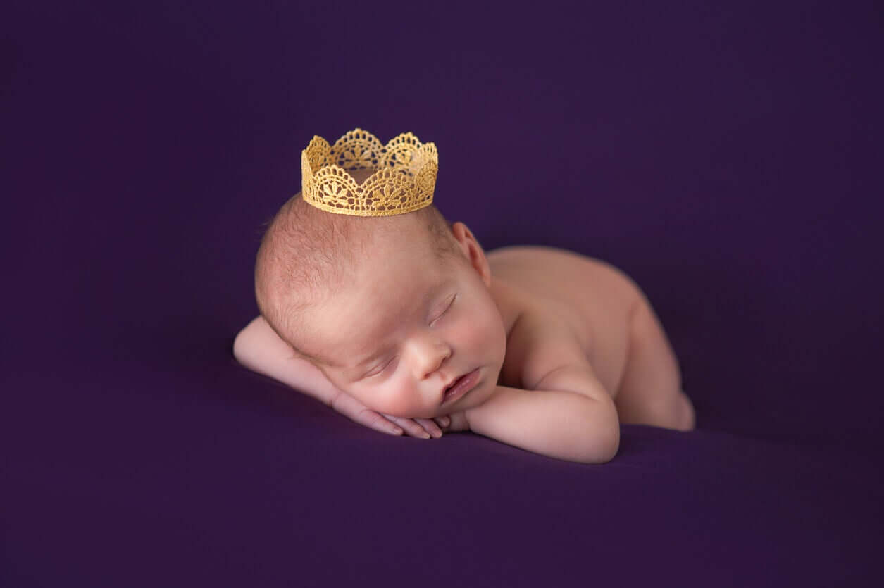 A sleeping neyborn wearing a tiny paper crown.