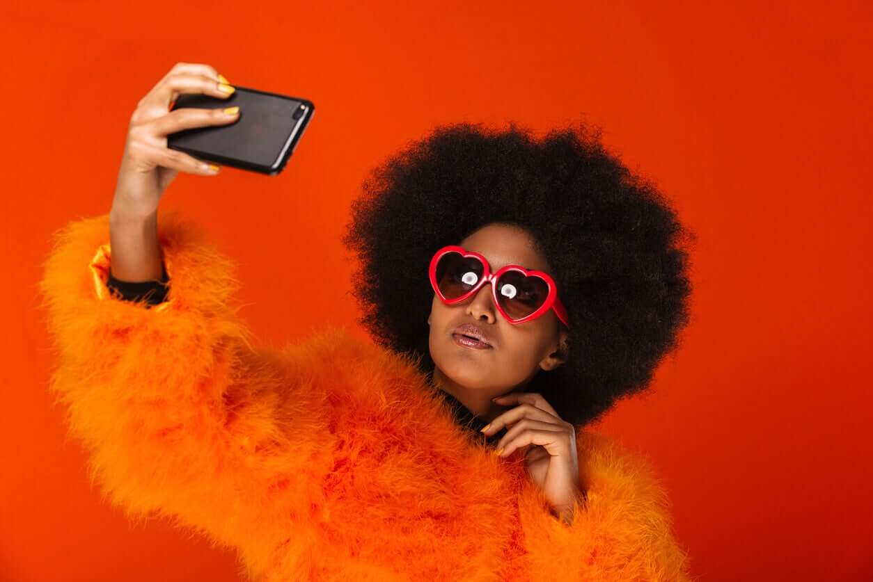 A teenage girl taking a selfie while wearing bright sunglasses.