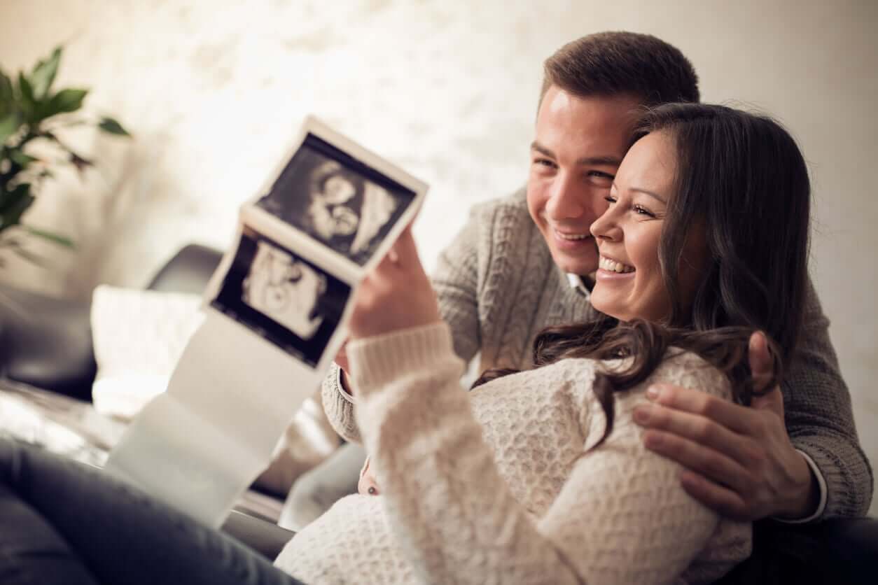 A pregnant couple looking at their ultrasound images.