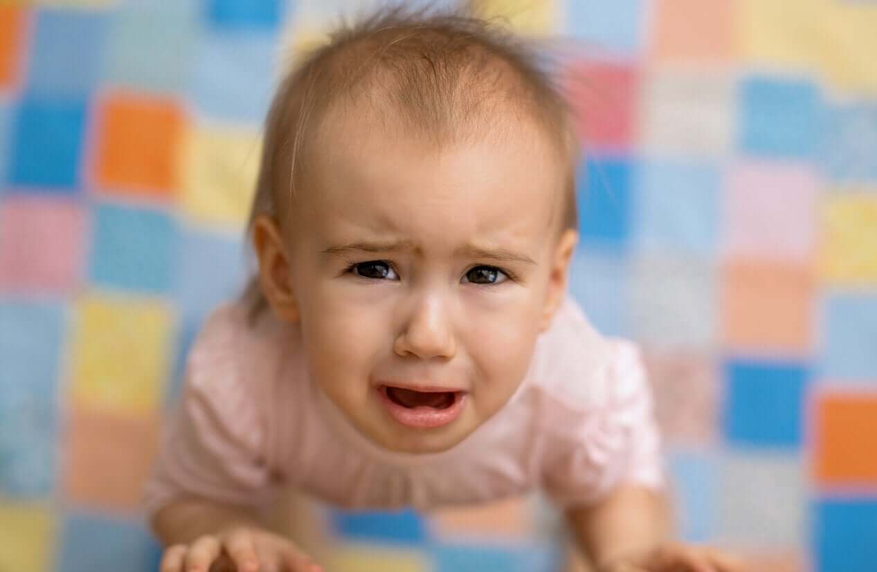 A baby girl looking up and crying.