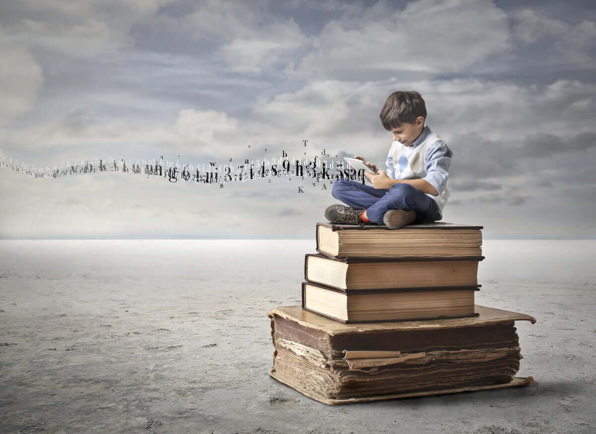 A child sitting on a pile of giant books using a tablet.