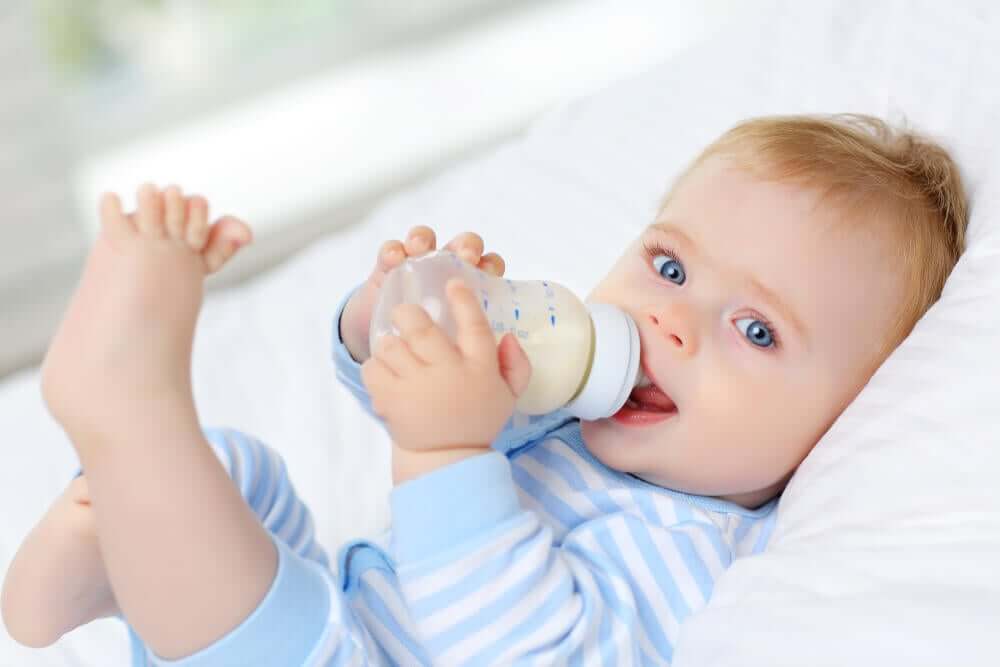 A baby drinking from a plastic baby bottle.