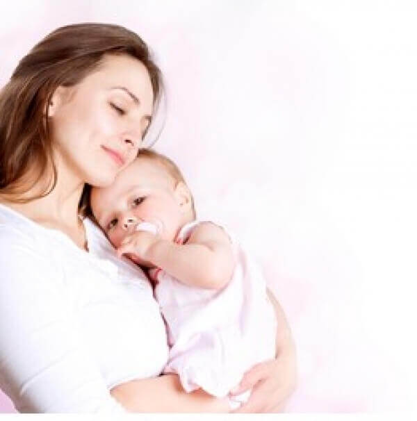 A baby girl resting her head on her mother's shoulder.