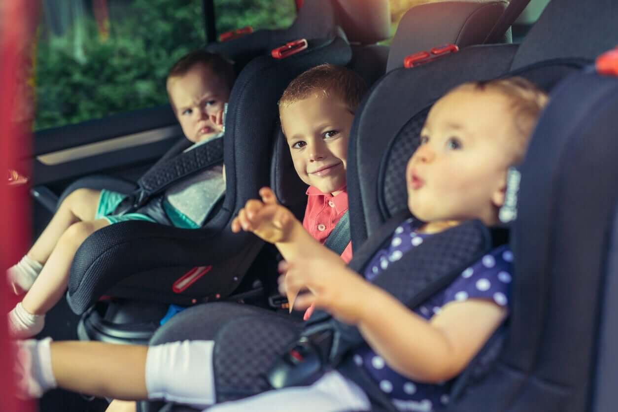 Three small chidlren travelling in car seats.
