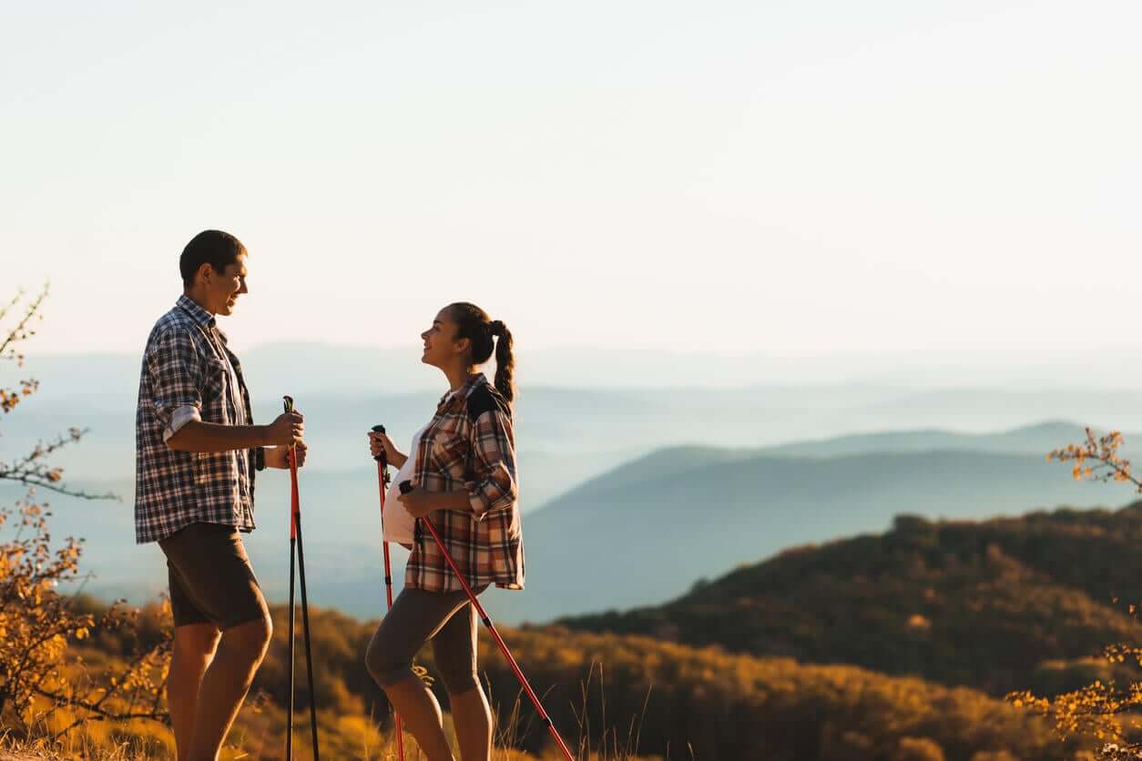 A pregnant couple hiking in the hills.