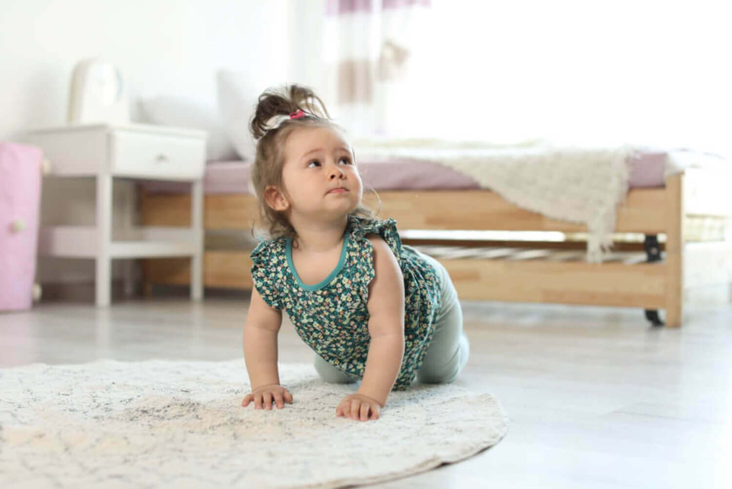 A baby girl crawling on the floor.
