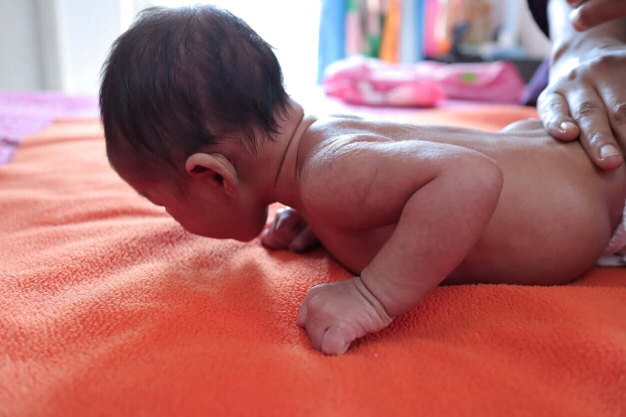 A small baby lying down and holding up his head.