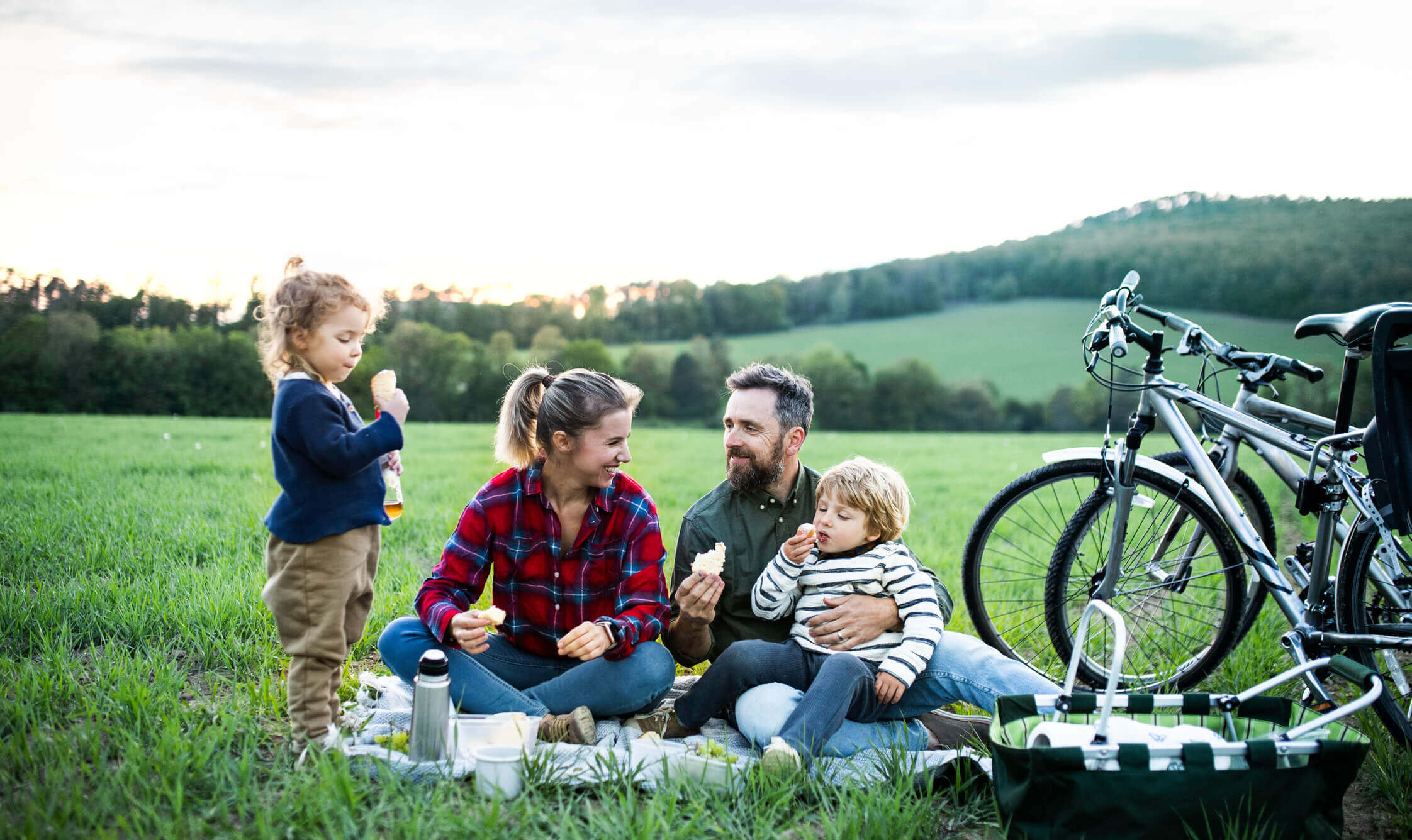 Föräldrar har picknick på landet med sina 2 småbarn efter en cykeltur.
