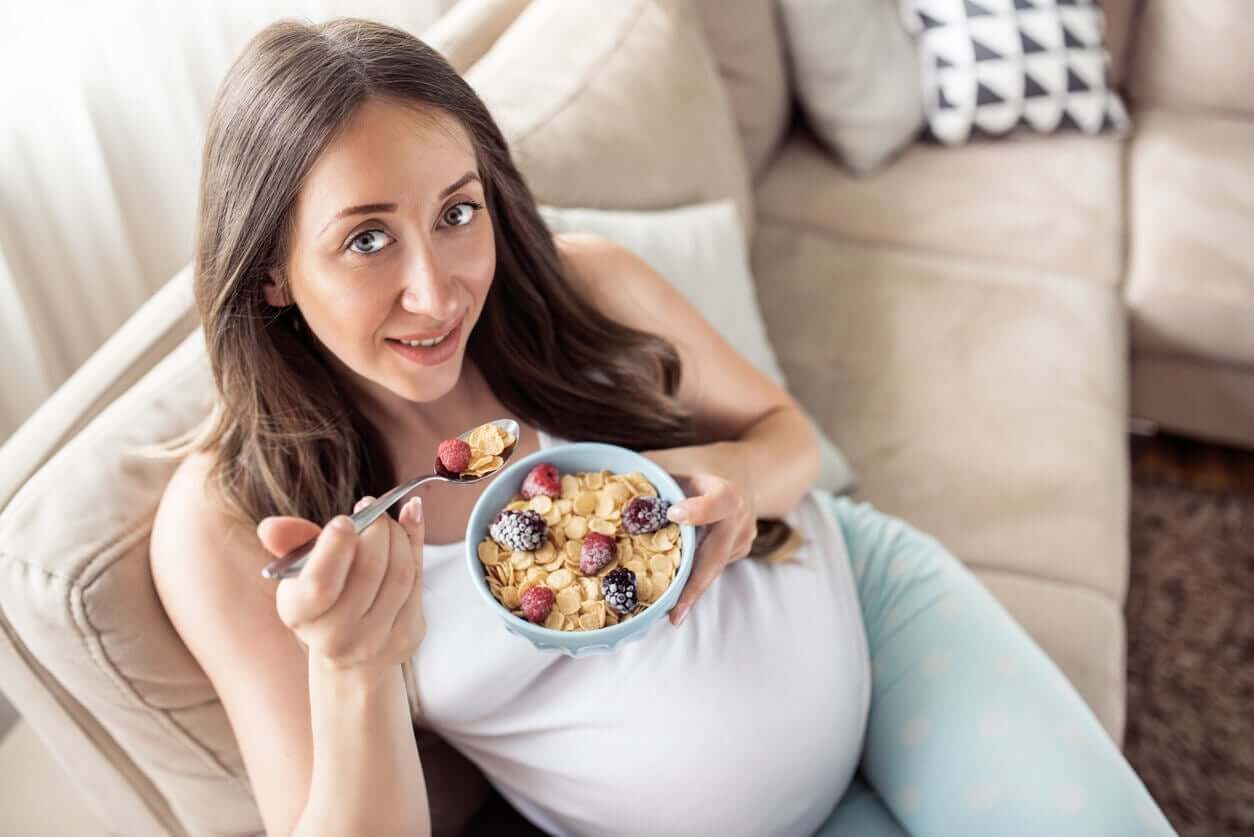 En gravid kvinne som spiser frokostblanding med bær.
