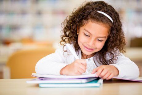 En liten flicka som skriver i en anteckningsbok.