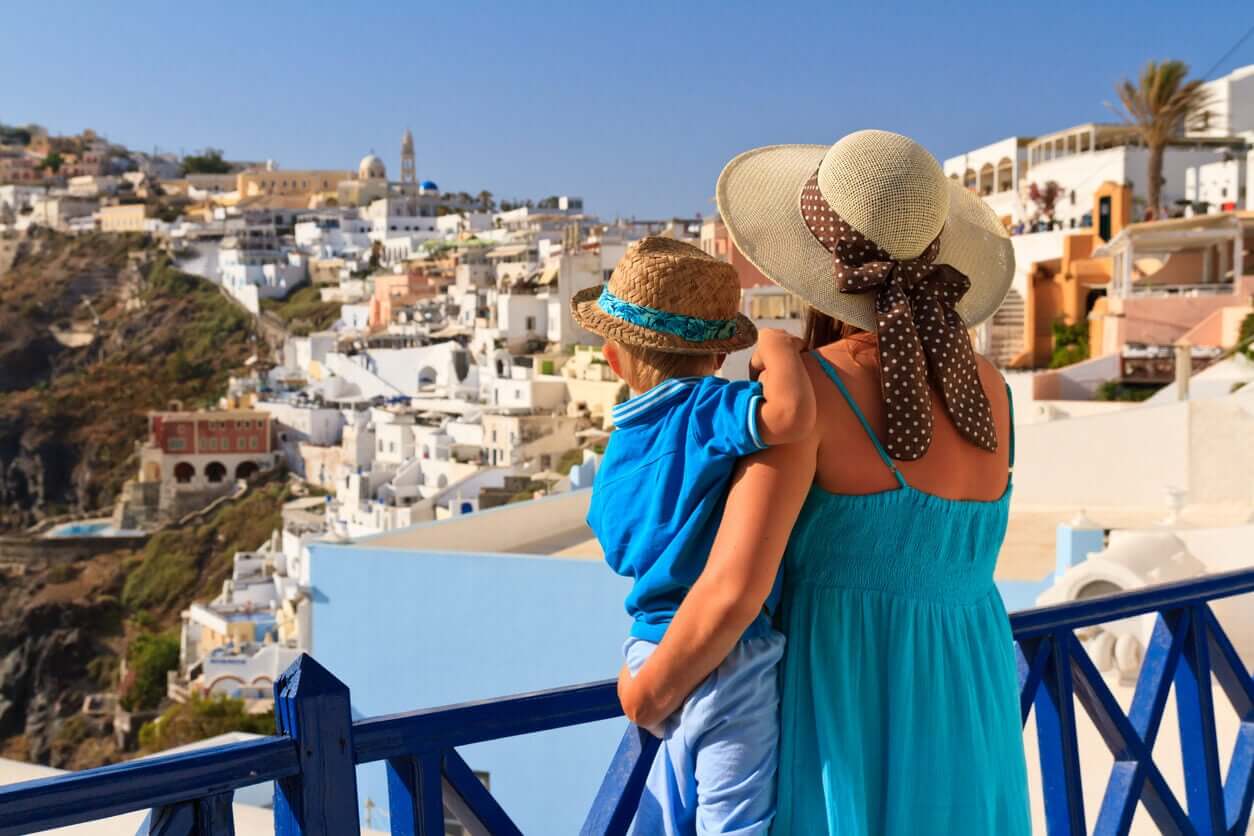 Äiti ja hänen lapsensa seisovat parvekkeella Kreikassa.