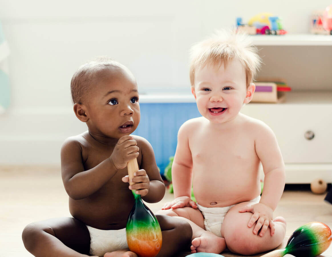 Två bebisar som sitter på golvet.