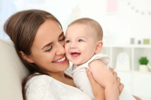 A mother rubbing her cheeck against her baby's cheek and smiling.