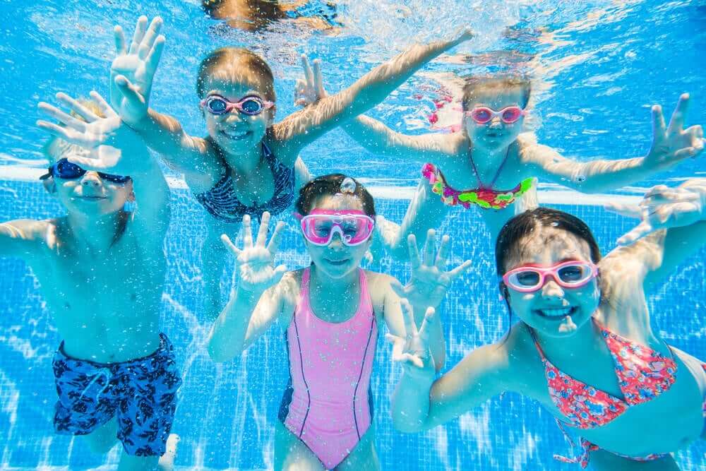 Children swimming underwater in a pool.