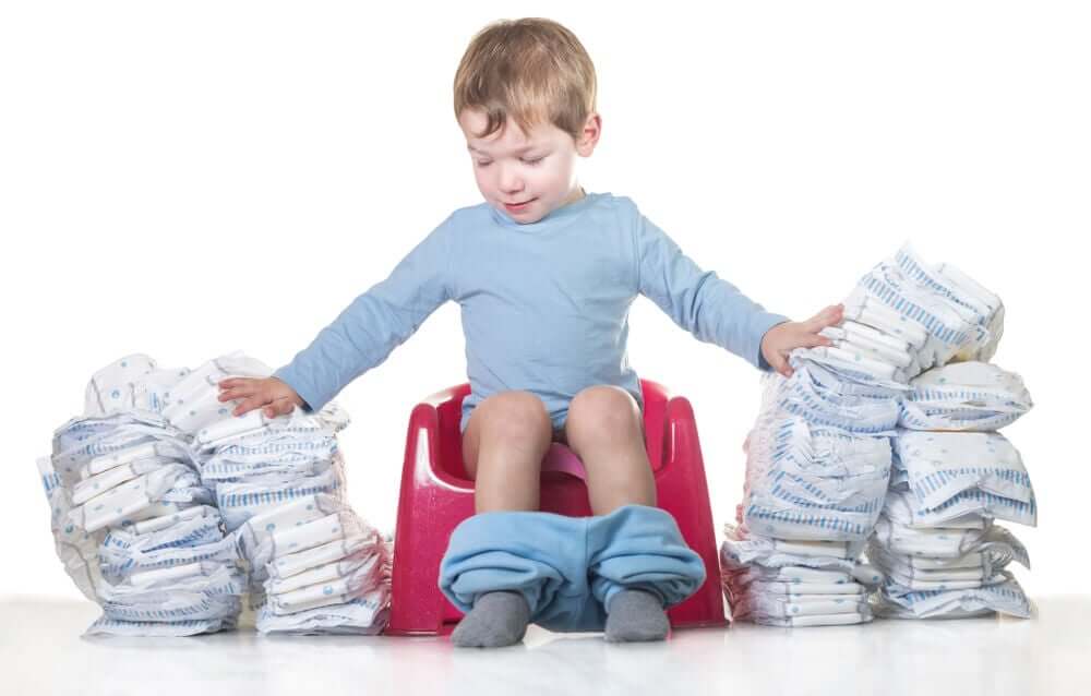 A toddler sitting on a potty surrounded by piles of diapers.