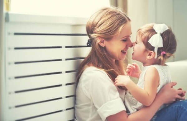 A mother and her daughter rubbing their noses together.