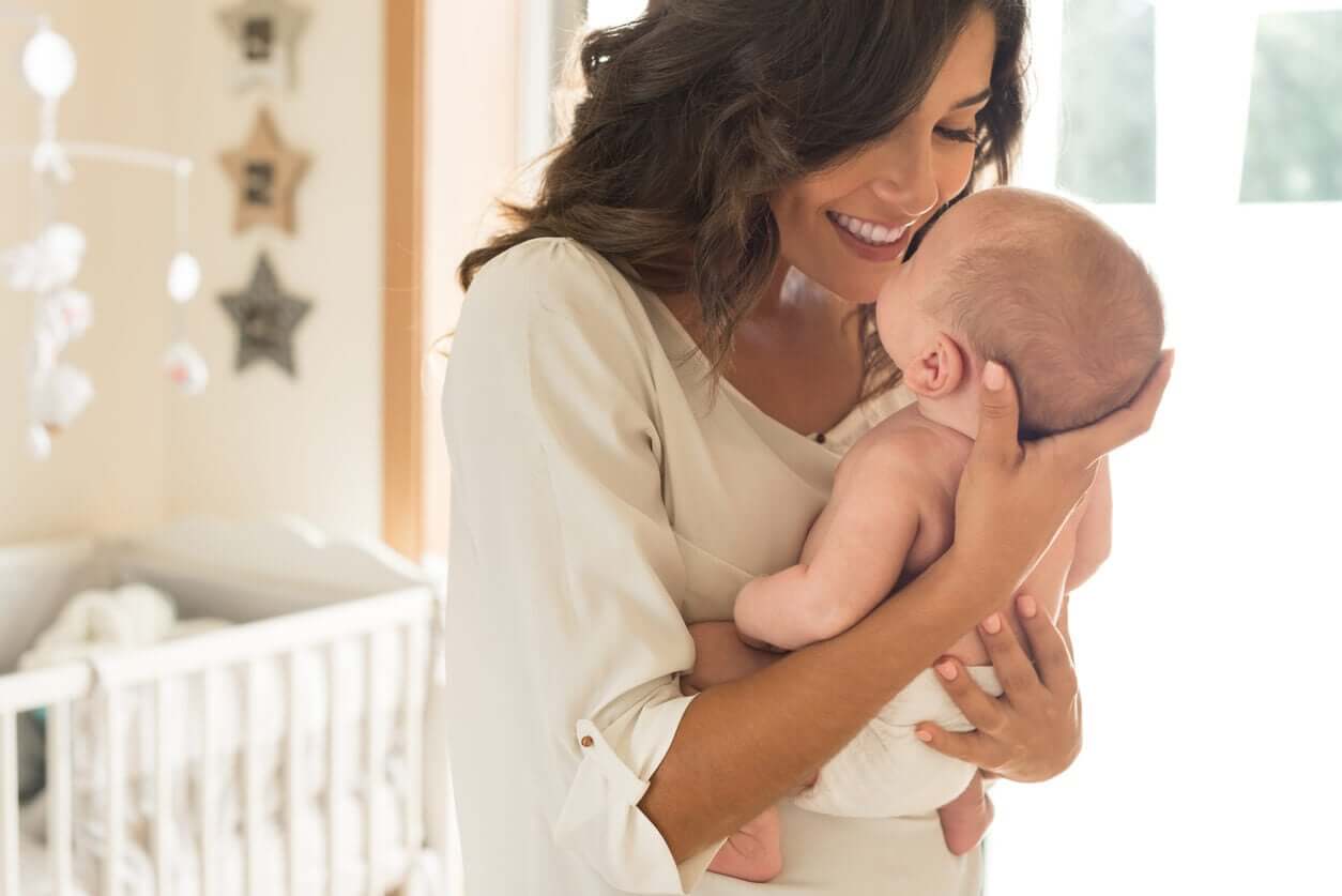 A mother holding her baby in her baby's room.