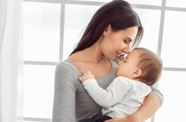 A mother snuggling her sleeping baby in her arms.