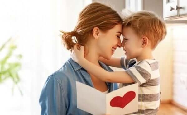 A little boy hugging his mom after giving her a card.