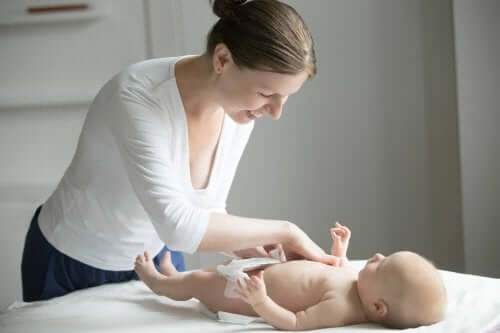 En kvinna byter blöja på en bebis.