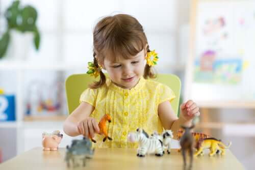 A little girl playing with toy animals.