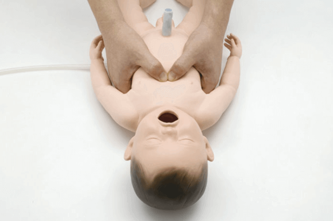 A person learning CPR with a baby mannequin.