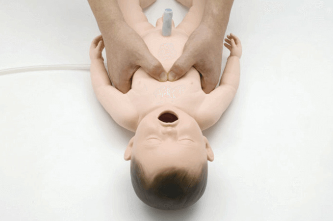 A person learning CPR with a baby mannequin. 