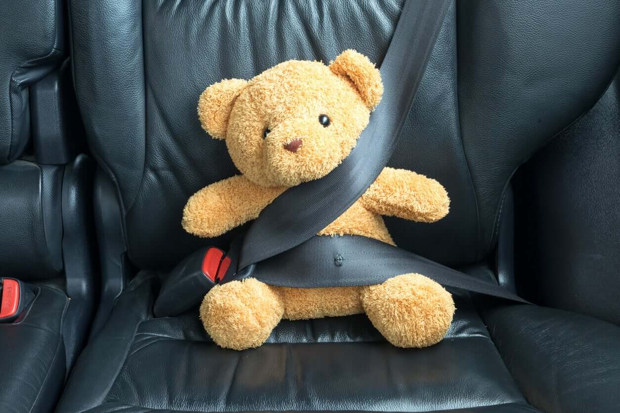 A teddy bear buckled into a car seat.
