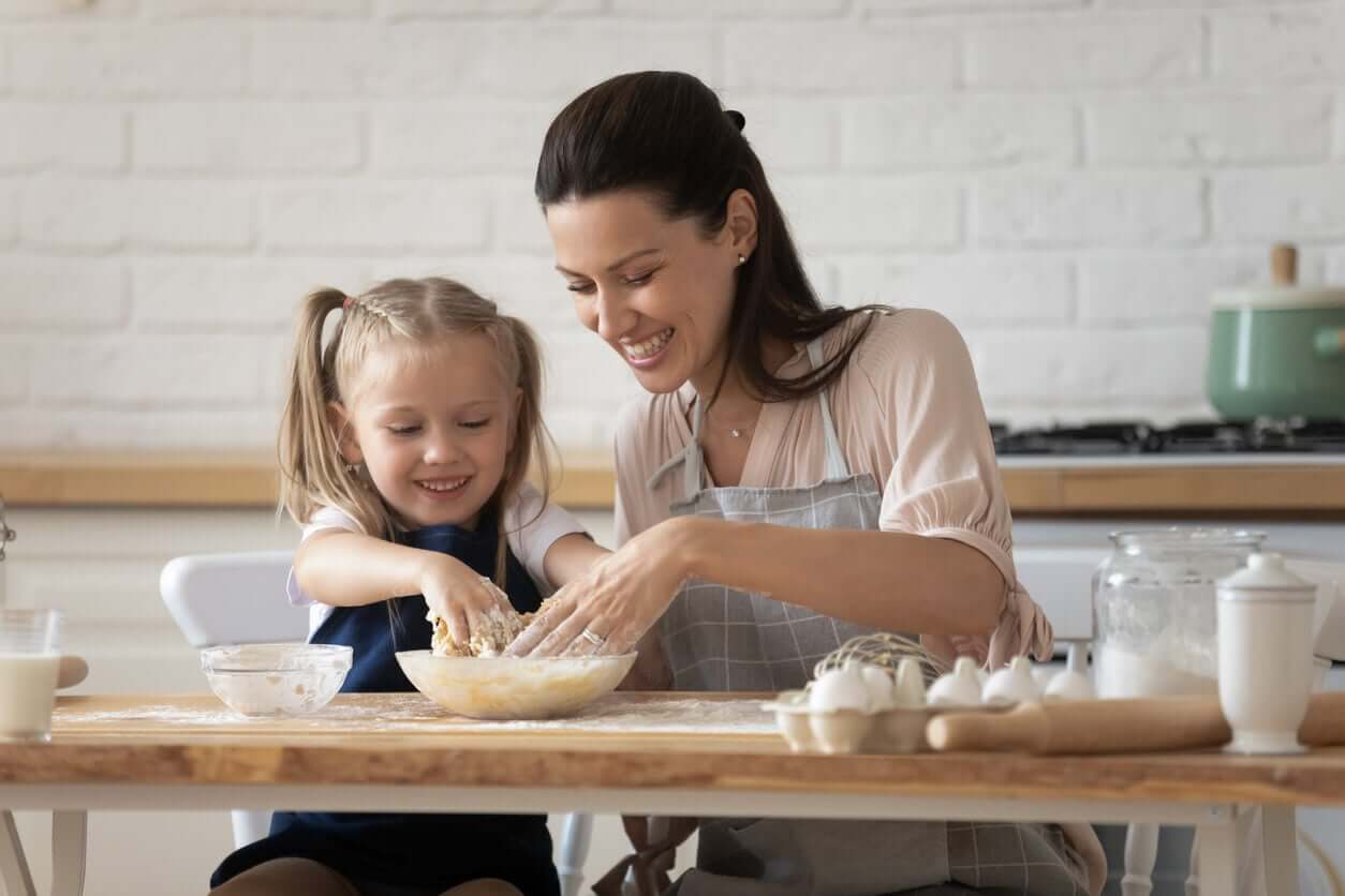A mother and her daughter mixing dough with their hands.