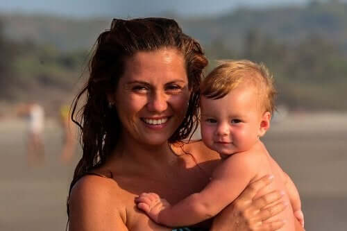A mother holding her baby boy at the beach.