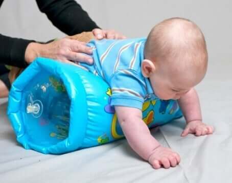 An adult using an inflatable pillow to stimulate crawling in babies.