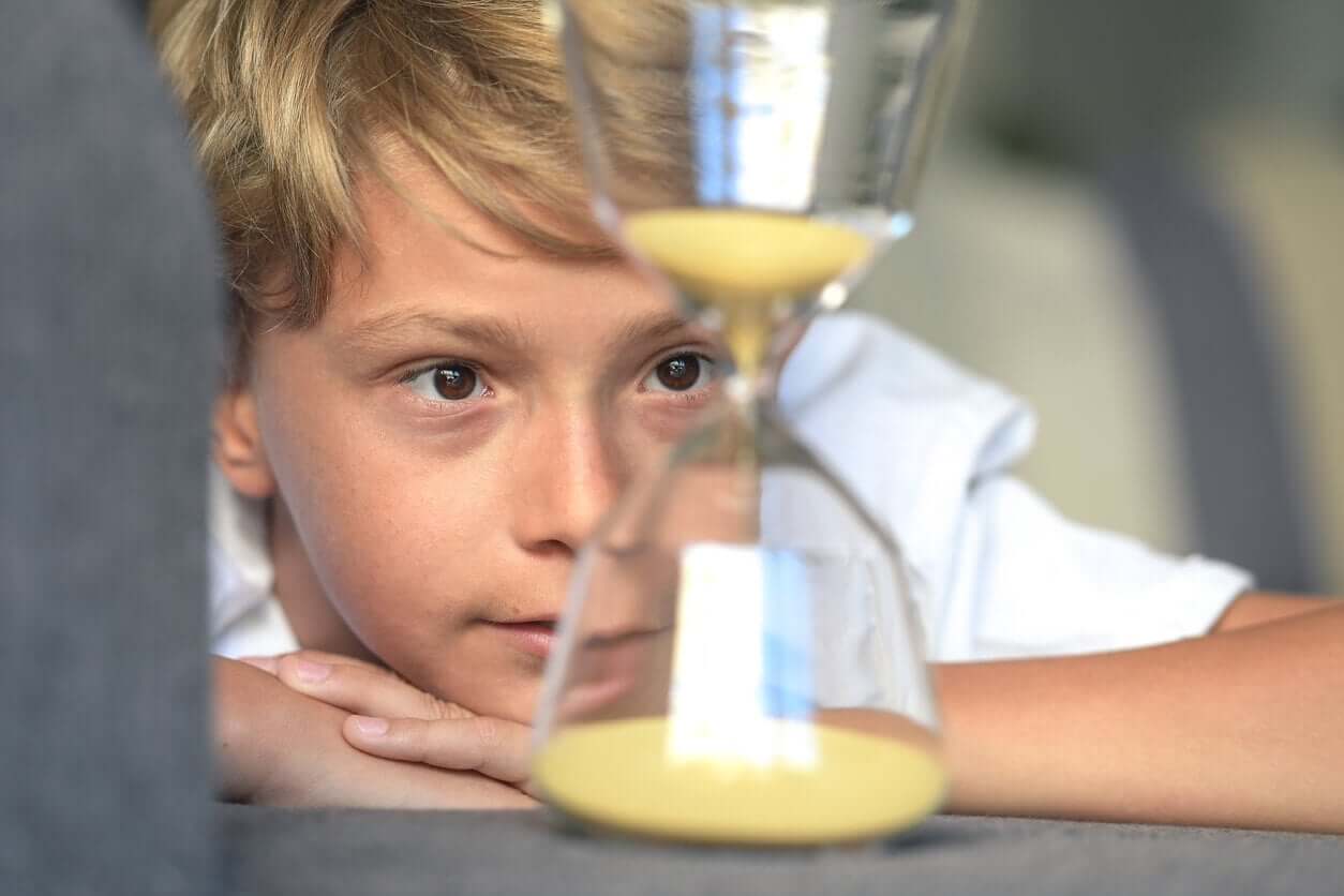 A child watching sand drop through and hour glass.