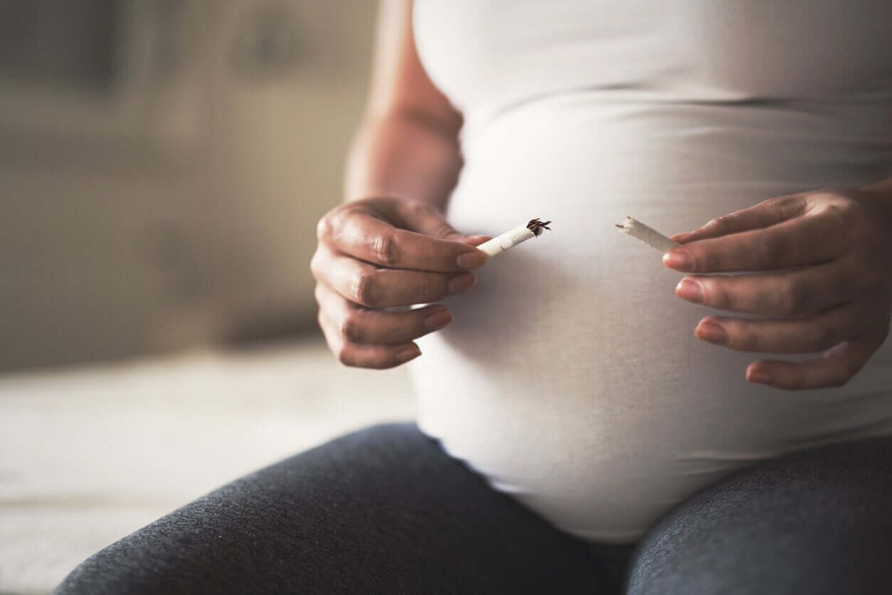 A pregnant woman breaking a cigarette in two.