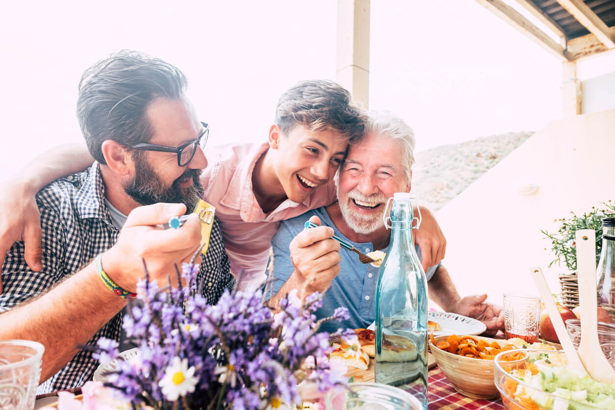 A teenage boy hugging his father and grandfather.
