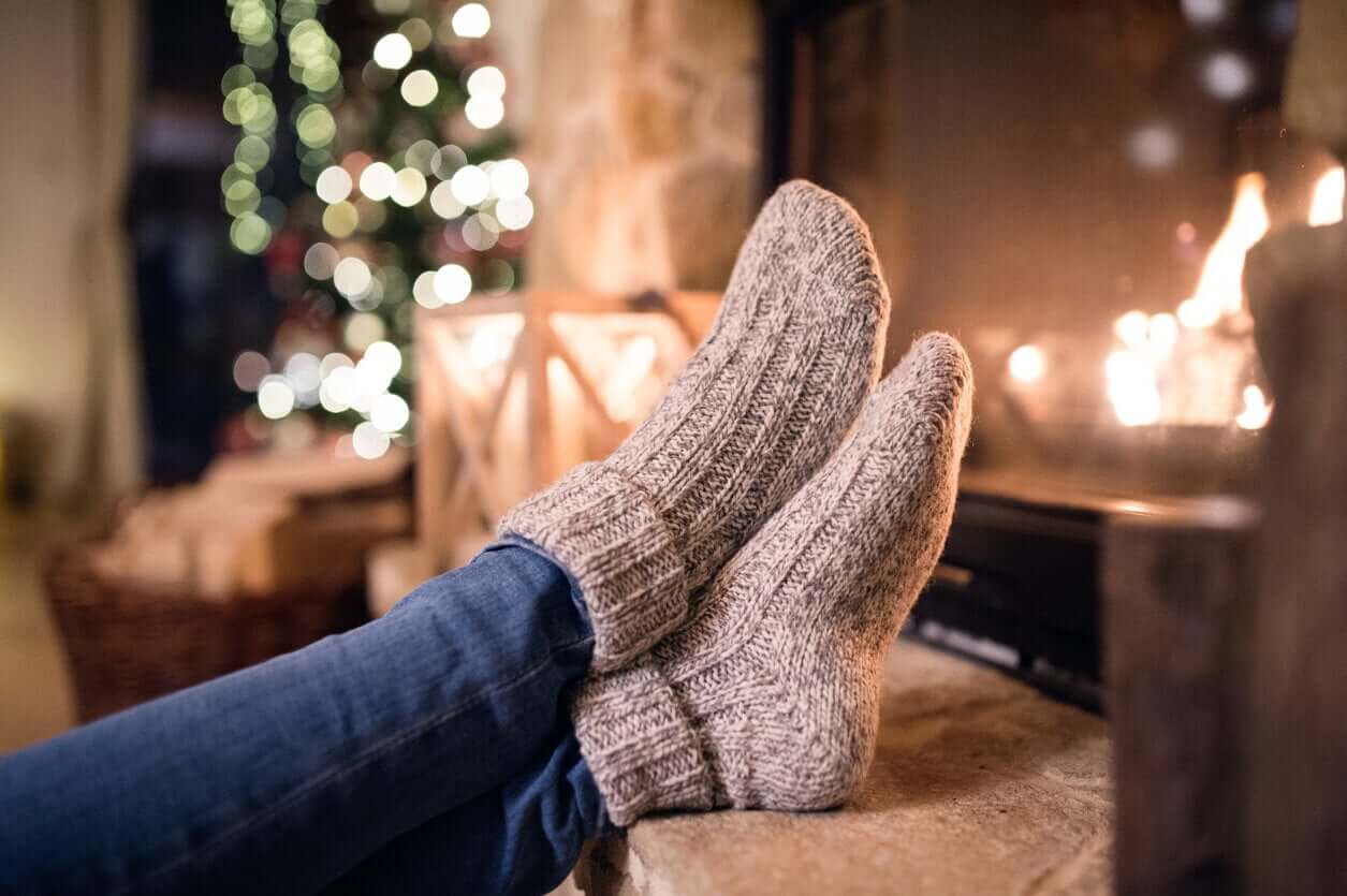 A woman warming her feet by a fireplace.