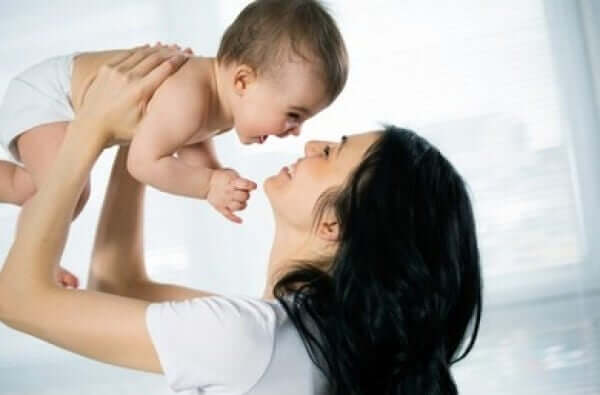 A mother holding her laughing baby in her arms.