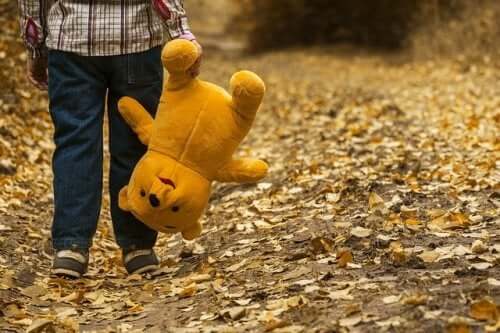 A child walking down a path holding a Winnie the Pooh toy.