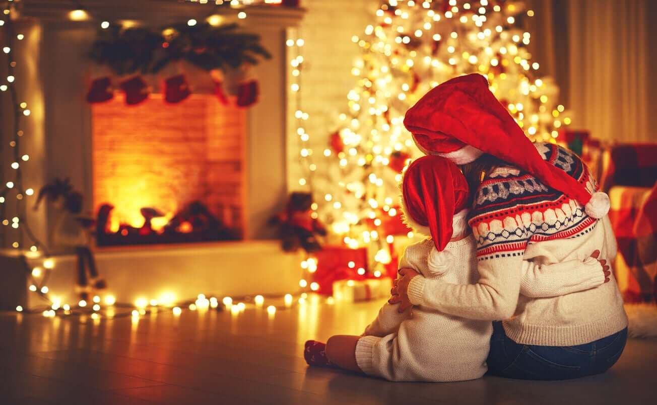 A mother and child embracing while looking at their christmas tree and stockings.
