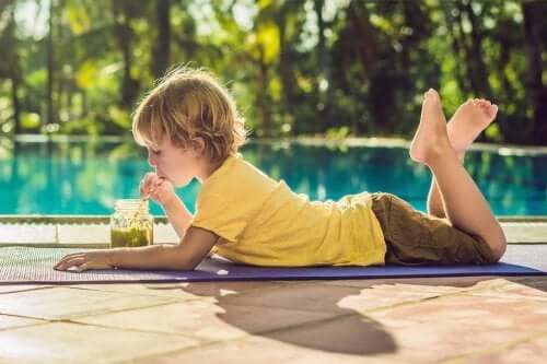 Ett barn som dricker en grön smoothie bredvid poolen.