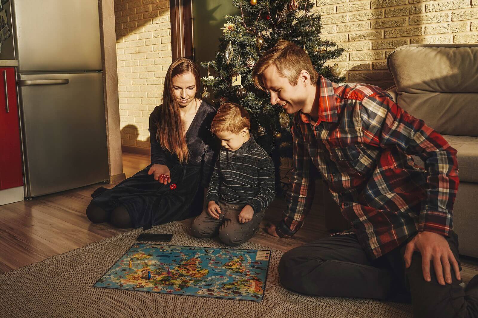 A family playing a board game by the Christmas tree.