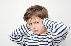 A boy with his hands over his ears.