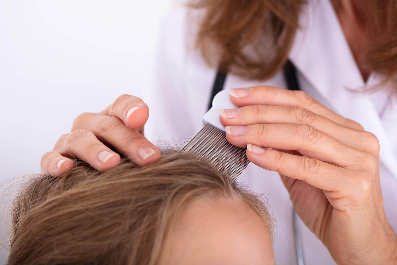 A woman checking a child's hair for lice with a nit comb.