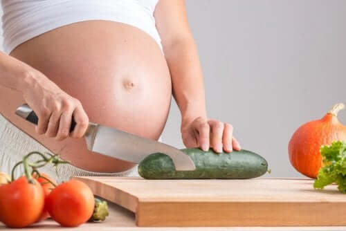 En gravid kvinne skjærer agurk.