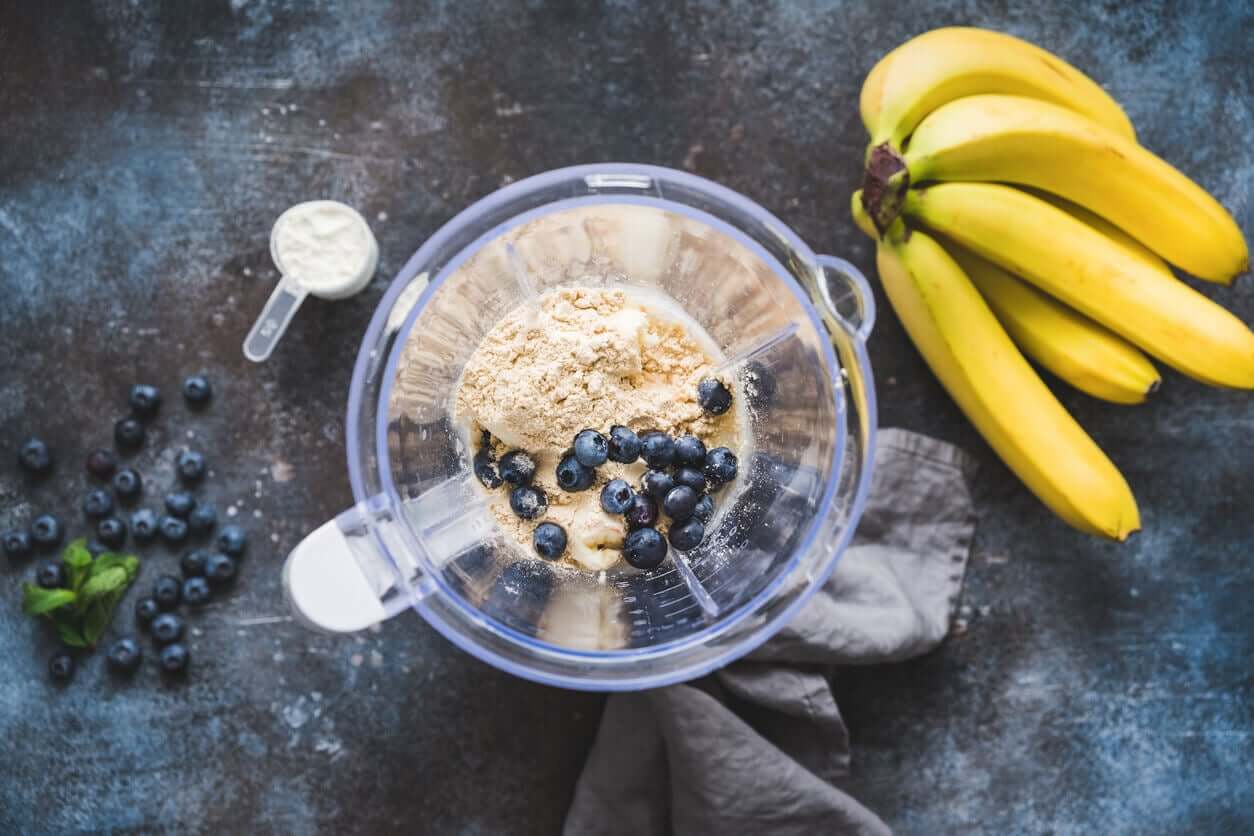 Banana, blueberries, and protein powder in a blender jug.