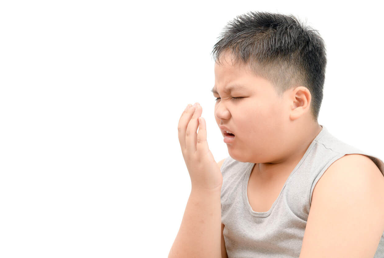 A boy smelling his own bad breath.