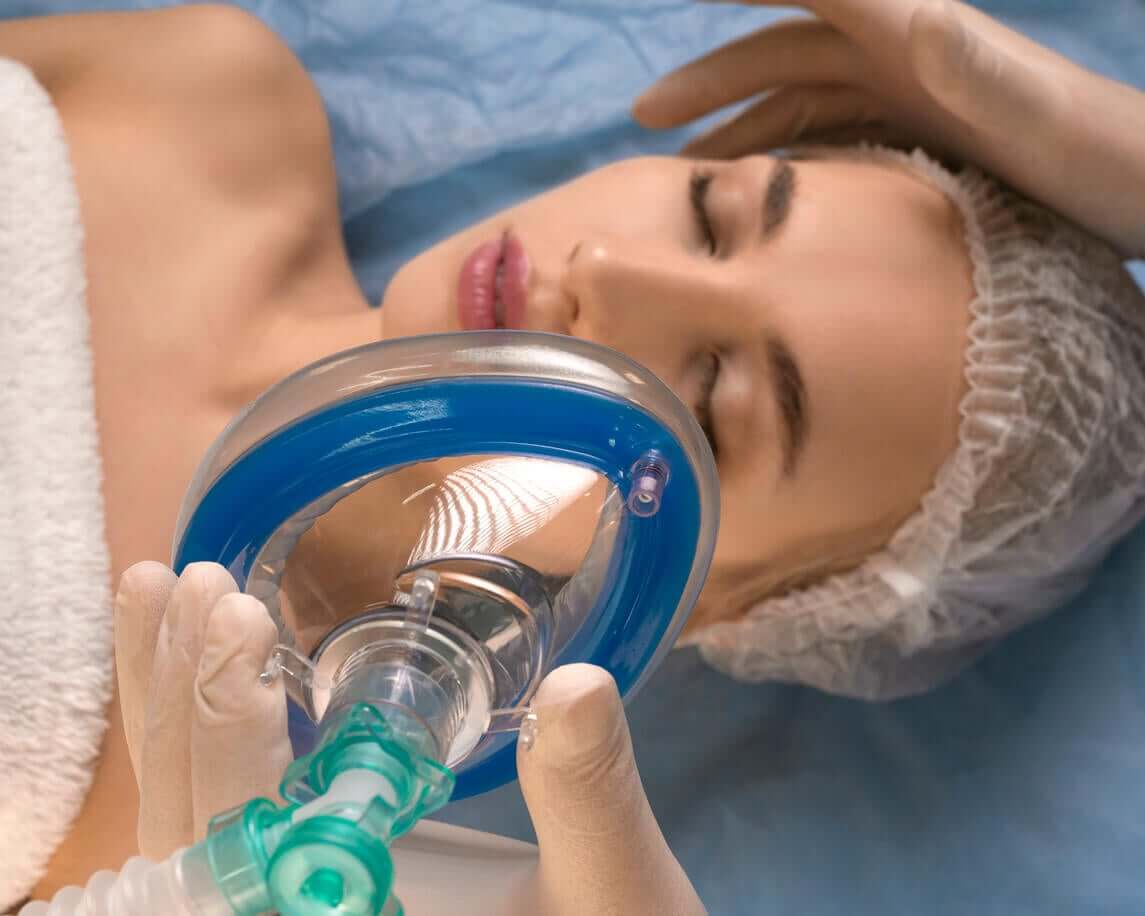 En lege legger en anestesimaske på en kvinnes ansikt.