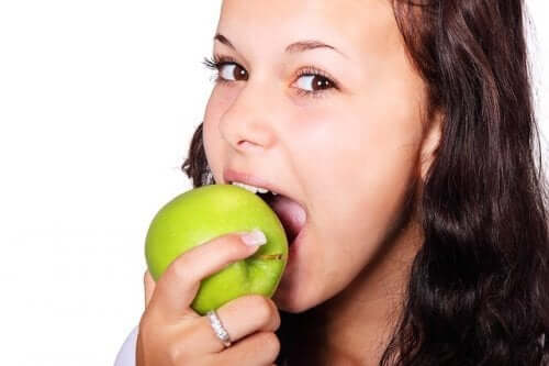 A woman biting into a green apple.